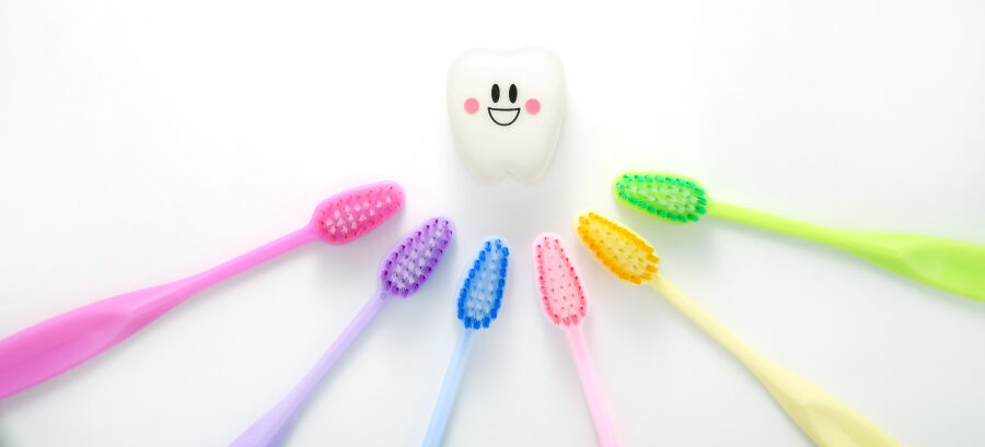 A rainbow of toothbrushes surround a smiling white tooth to represent choosing from different dentists