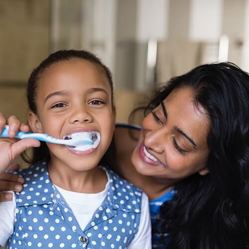 mother and daughter brushing their teeth together