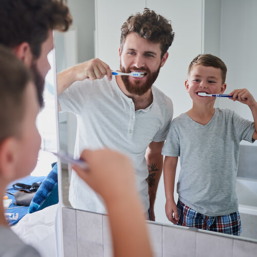 father and son brushing their teeth together