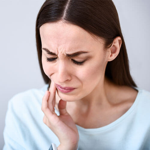 woman holding her jaw in pain