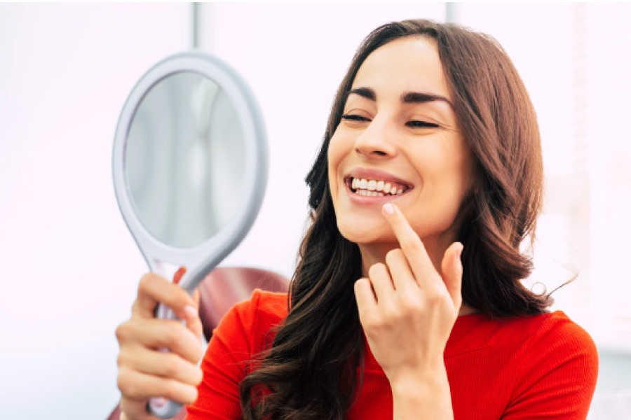 woman hold a mirror to inspect her gums