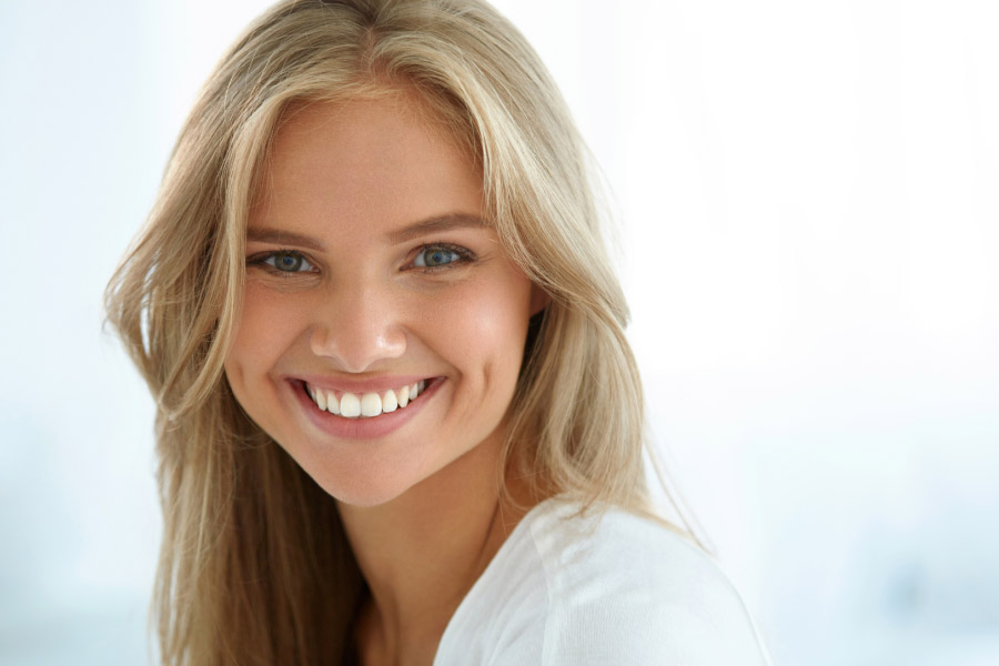 young woman smiles showing off her perfect teeth